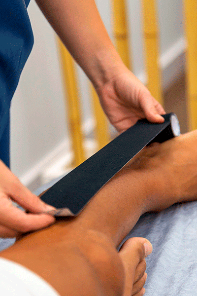 manos-colocando-vendaje--para-fortalecer-los-ligamentos-y-tendones-del-tobillo--en-clinica-fisioterapia-almeria-Fernando-Arco-Centro-de-Fisioterapia