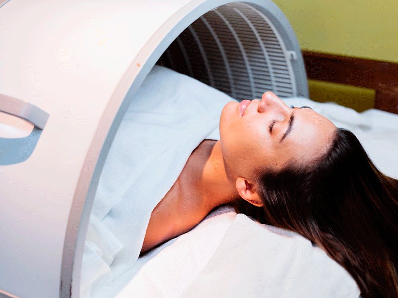 Mujer con pelo negro y ojos cerrados tumbada realizando tratamiento de Magnetoterapia