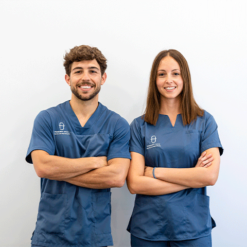 Equipo de Fisioterapeutas en Almería de Fernando Arco Centro de Fisioterapia en Almería posando para una foto con brazos cruzados y traje azul con fondo blanco