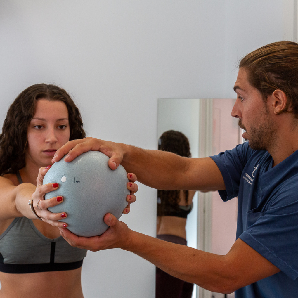Ejercicio Terapéutico en Fernando Arco Centro de Fisioterapia en Almería Fisioterapeuta guiando a una paciente en ejercicio de readaptación con balón terapéutico en Fernando Arco Centro de Fisioterapia en Almería